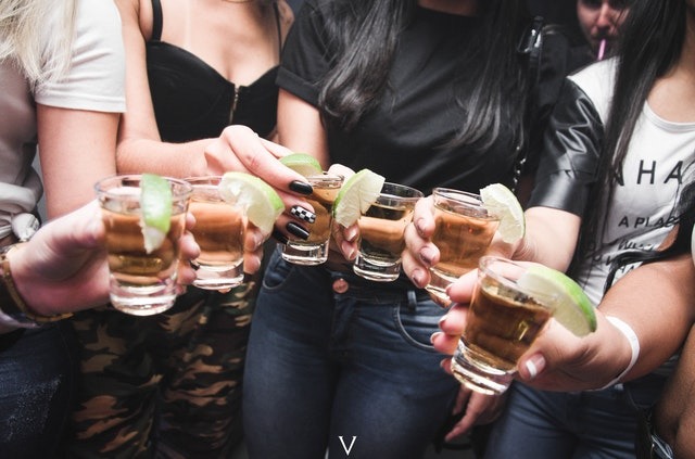 women holding shot glasses drinking